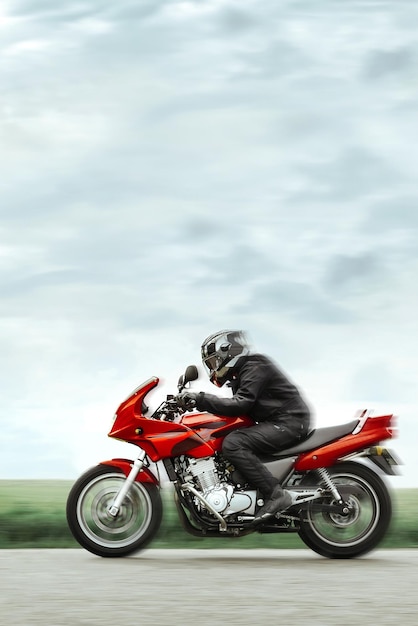 Motociclista em roupas de proteção monta rapidamente uma motocicleta esportiva