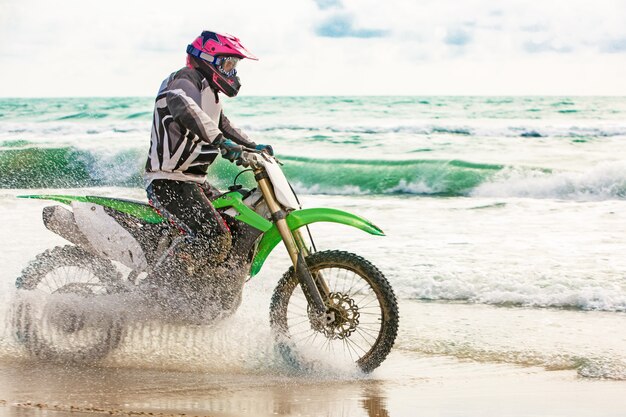 Motociclista em um traje de proteção anda de moto à beira-mar