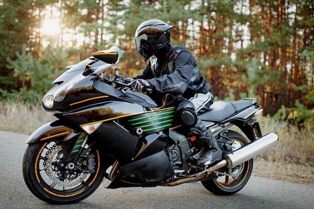Motociclista em uma estrada florestal. divirta-se em uma estrada vazia em uma motocicleta esportiva. copie o espaço para o seu texto personalizado