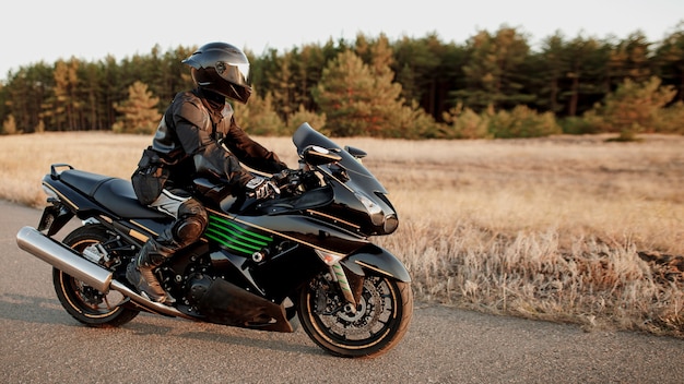 Motociclista em uma estrada florestal. Divirta-se em uma estrada vazia em uma motocicleta esportiva. Copie o espaço para o seu texto personalizado