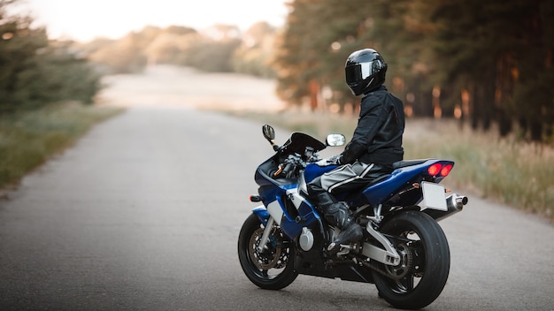 Motociclista em uma roupa de proteção com um capacete. motociclista de capacete e jaqueta de couro na estrada em uma motocicleta esportiva