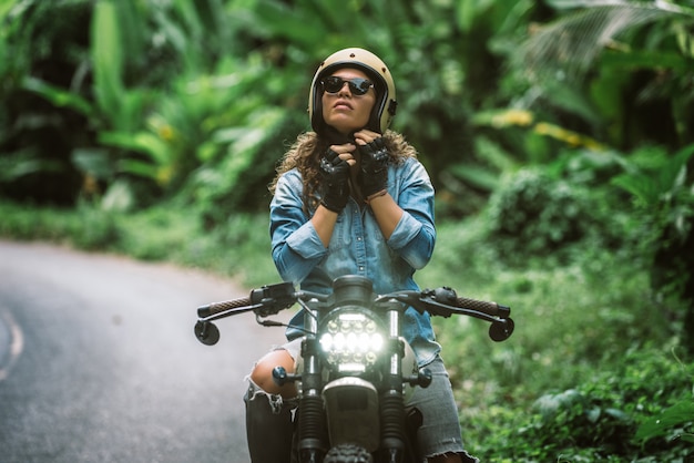 Motociclista feminina dirigindo uma moto de café piloto