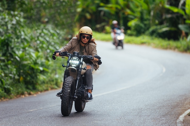 Motociclista feminina dirigindo uma moto de café piloto