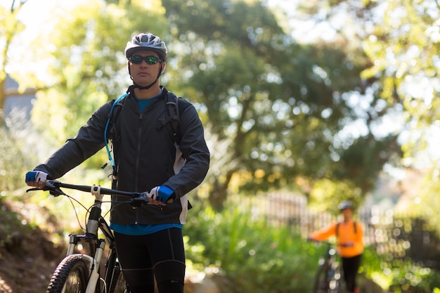 Motociclista masculina em pé com bicicleta de montanha