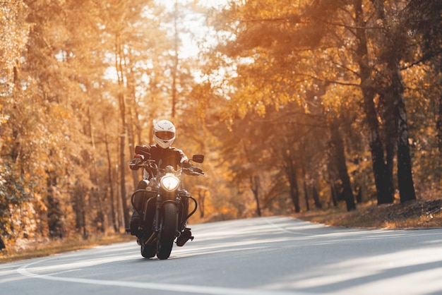 Motociclista masculina que monta a motocicleta preta brilhante