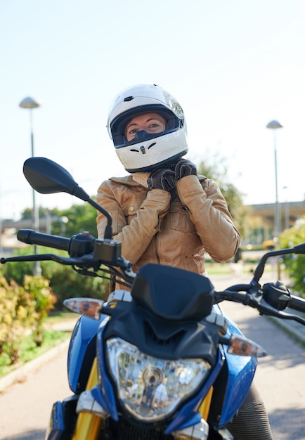 Motociclista mujer ajustando su casco, concepto de seguridad en la carretera