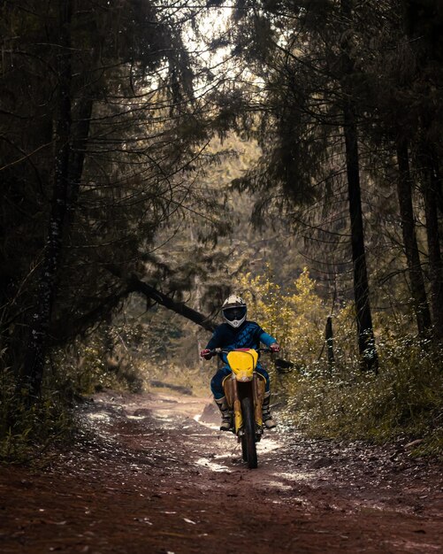 Motociclista profissional na floresta passa pela lama na estrada natural