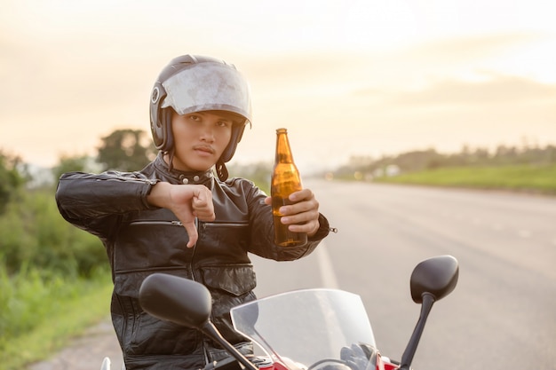 Motociclista sentado em sua motocicleta, mostrar a mão com o símbolo não beber álcool ou cerveja