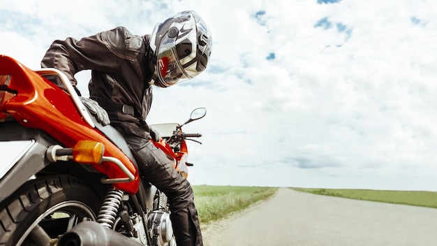 Foto motociclista sentado em uma motocicleta olhando para a roda traseira