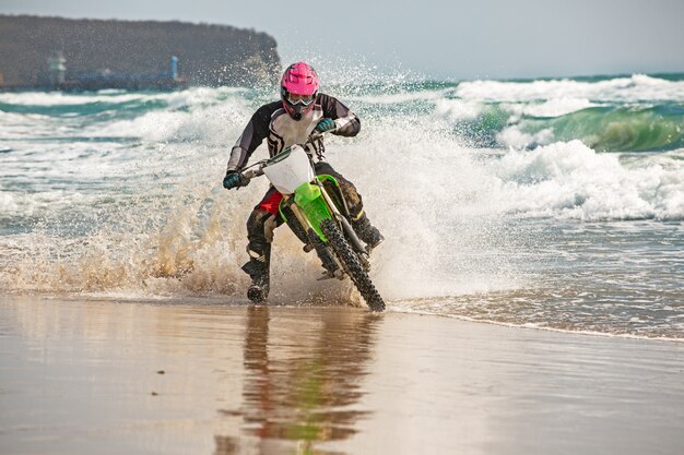 Motociclista en un traje de protección monta una motocicleta en el mar