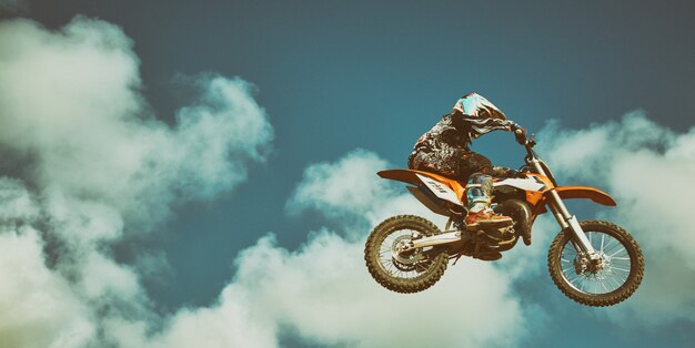 Motociclista voando no céu azul. conceito extremo, salto em distância em uma motocicleta.