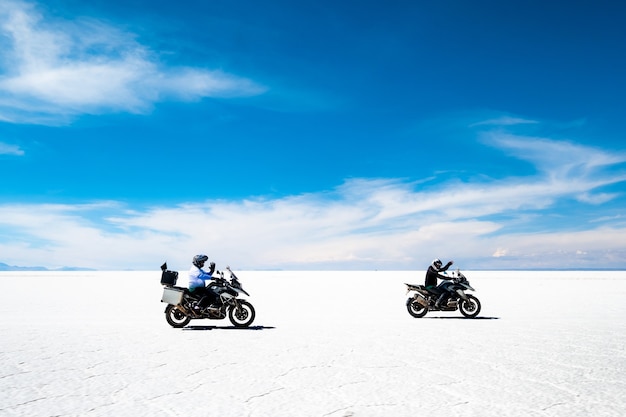 Motociclistas y paseos en coche bajo el sol salar de uyuni