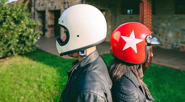 Foto motociclistas usando capacetes de choque de pé de costas para trás no quintal