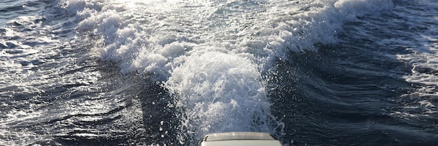 Motor de barco y rastro de agua con olas y espuma detrás de él Viajes de turismo marino y pesca en el mar
