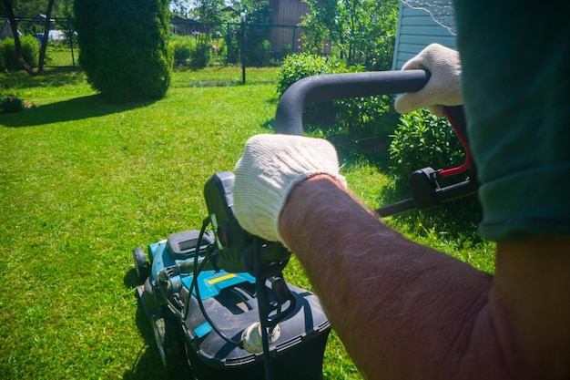 Motor de césped sobre hierba verde en un jardín o patio trasero moderno Máquina para cortar césped Herramientas y equipos para el cuidado de la jardinería Proceso de recorte de césped