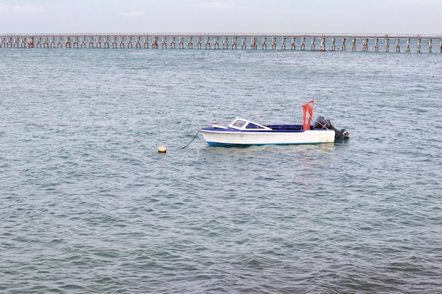 Motorboot mit weißer Farbe und blauer Farbe im Inneren, in dem niemand auf dem Meer schwimmt