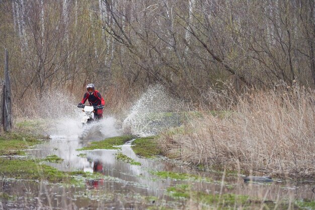 Motorcross-Fahrer, die während des Wettbewerbs in der natürlichen Umgebung in Pfützen rennen