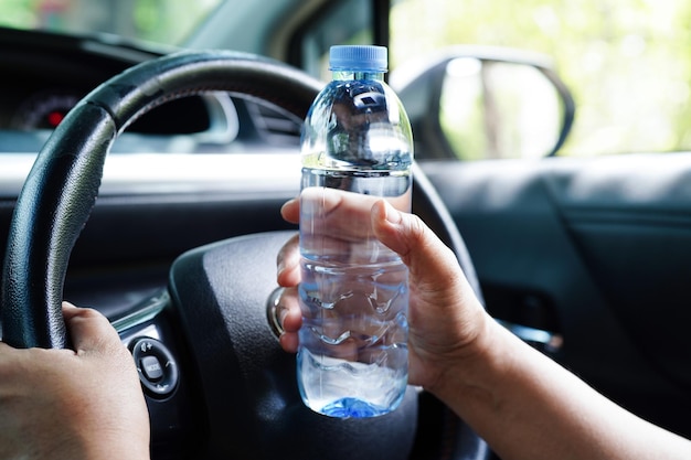 Motorista asiática segura água fria para beber no carro perigoso e arrisca um acidente