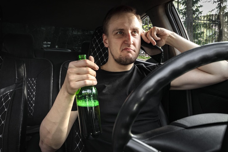 Foto motorista bêbado agressivo com uma garrafa de álcool a conduzir um carro a falar ao telefone conceito de condução alcoólica
