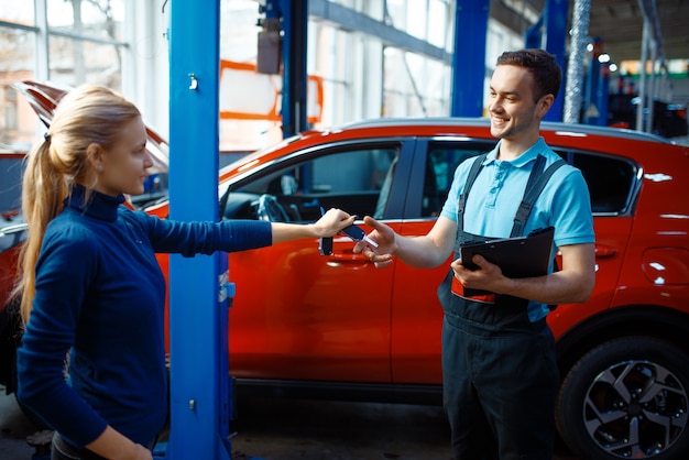 Motorista dá chaves para trabalhador de uniforme, posto de gasolina. Verificação e inspeção de automóveis, diagnósticos profissionais e reparos