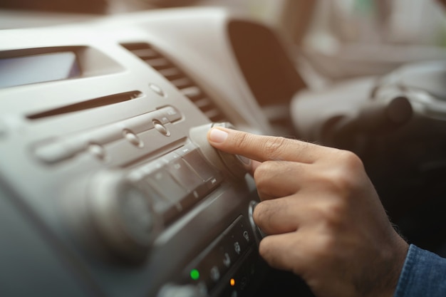 Motorista de carro mudando o botão de giro Estações de rádio em seu veículo