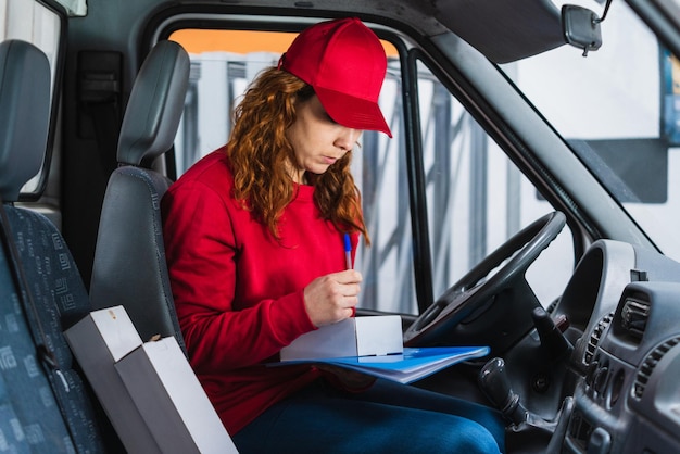 Motorista de entrega feminina assinando um pacote no carro