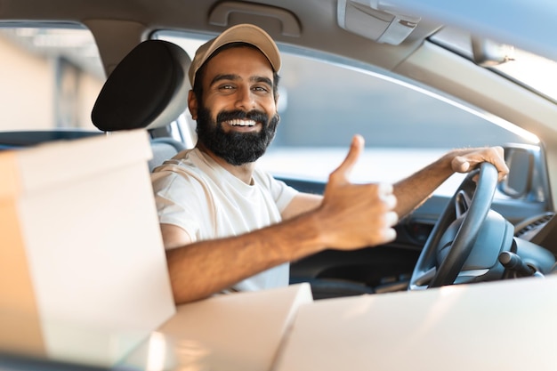 Motorista de entregador indiano gesticulando polegares para cima sentado no carro