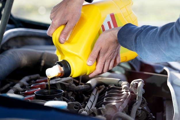 Foto motorista de homem derramando e reabastecendo a qualidade do óleo no automóvel, closeup.