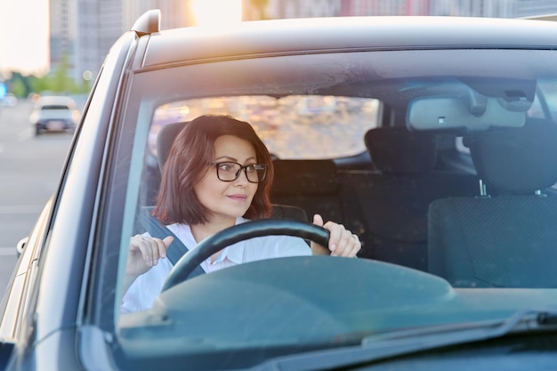 Motorista de meia idade com óculos femininos dirigindo um carro