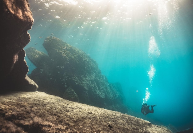 Motorista de mergulho em um vestido especial explorando os riffs subaquáticos do oceano azul