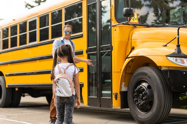 Foto motorista de ônibus sorridente olhando para a câmera fora da escola primária