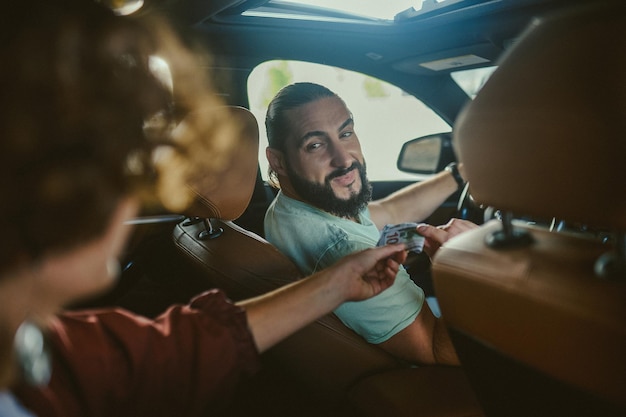 Motorista de táxi Um jovem motorista blindado em um carro com uma cliente do sexo feminino