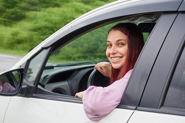 Motorista jovem alegre sorrindo enquanto dirigia o carro.