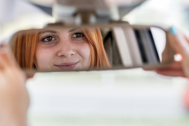 Motorista jovem verificando o espelho retrovisor enquanto dirigia um carro