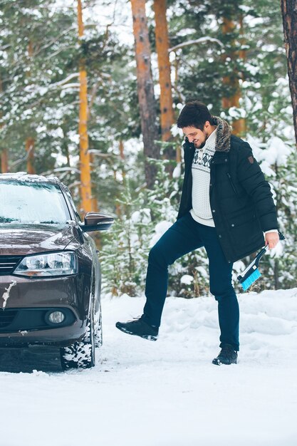 Motorista malvado chuta o volante de um carro no inverno na floresta