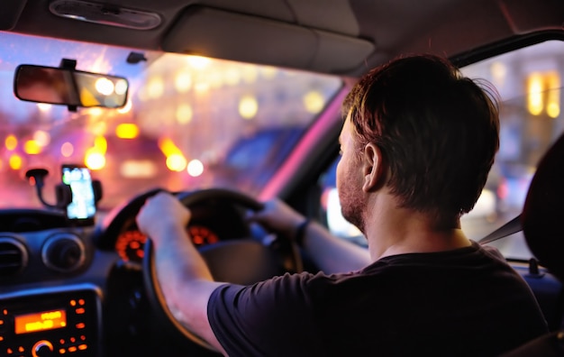 Motorista masculina andar de carro durante o engarrafamento à noite