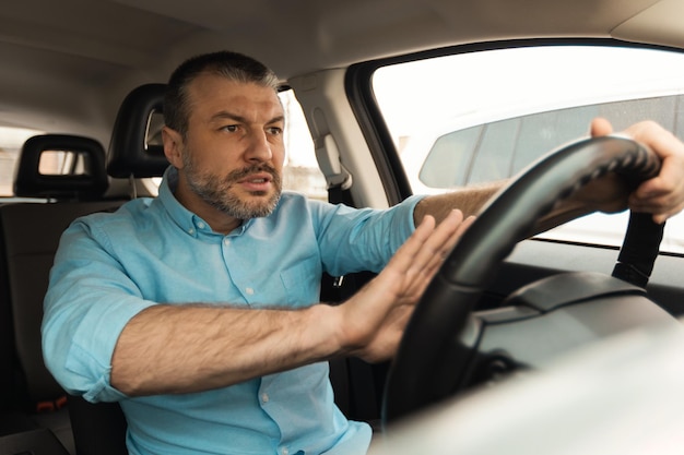 Motorista masculino descontente buzinando a buzina dirigindo o carro na cidade