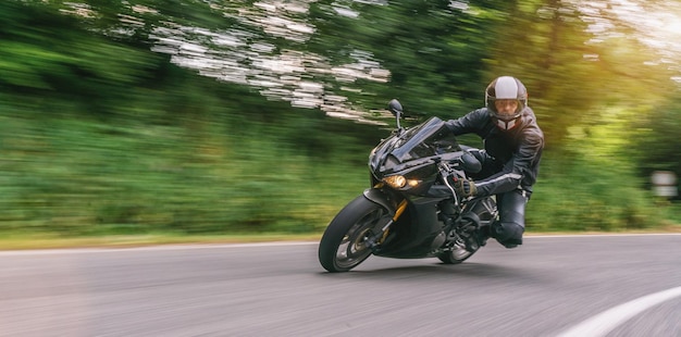 Foto motorradfahren auf der forststraße in einer kurve. fahren auf der leeren straße auf einer motorradreise. exemplar für ihren individuellen text.