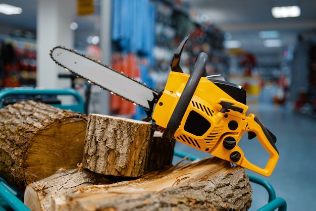 Foto motosierra y tocón de madera en el escaparate de la tienda de herramientas eléctricas closeup, nadie. elección de equipo en ferretería, instrumento eléctrico en supermercado