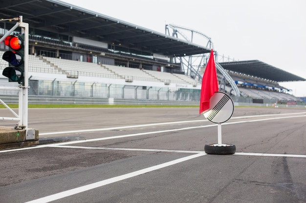 motosports, concepto extremo y de carrera - cierre de semáforos rojos y señales de carretera con bandera en pista o carretera