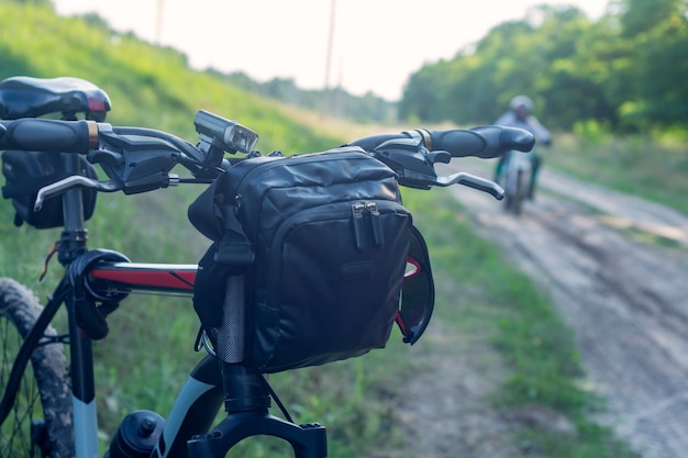 Mountainbike mit Tasche am Lenker vor dem Hintergrund von Motorradfahrern.