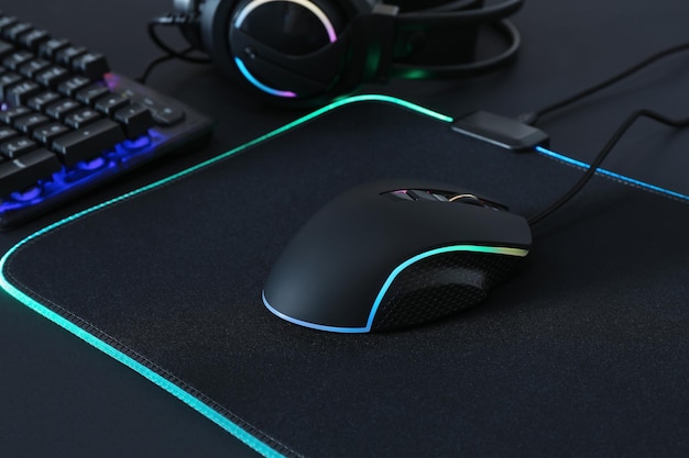 Mouse de computadora mousepad teclado RGB y auriculares sobre fondo negro