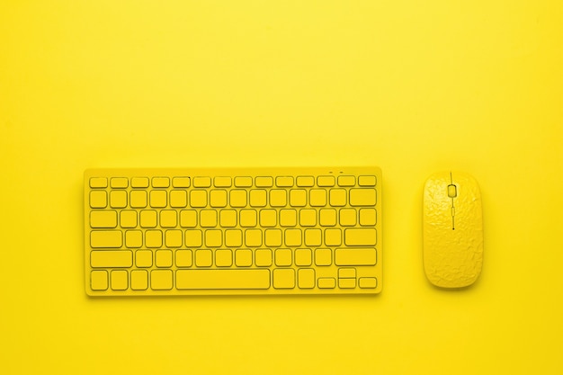 Mouse e teclado amarelos do computador em um fundo amarelo.