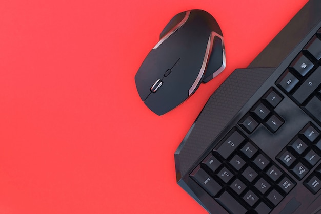 Mouse preto, teclado isolado em um fundo vermelho, vista superior. Fundo de jogador plana leigos.