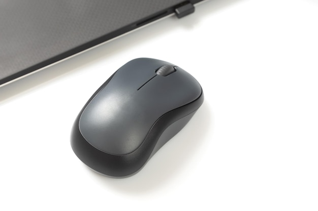 Mouse sem fio de computador ao lado de um laptop em uma mesa branca closeup indústria pessoal eletrônica