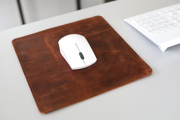 Mousepad de cuero aislado en el escritorio de oficina con ratón blanco