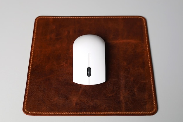 Mousepad de cuero aislado en el escritorio de oficina con ratón blanco