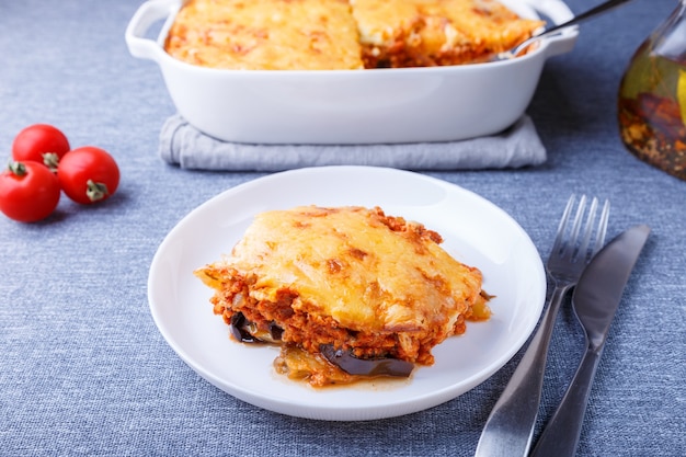 Moussaka com carne, beringela, tomate, batata, molho bÃƒÂƒÃ‚Â © chamel e queijo num prato branco. Prato tradicional grego. Fechar-se.