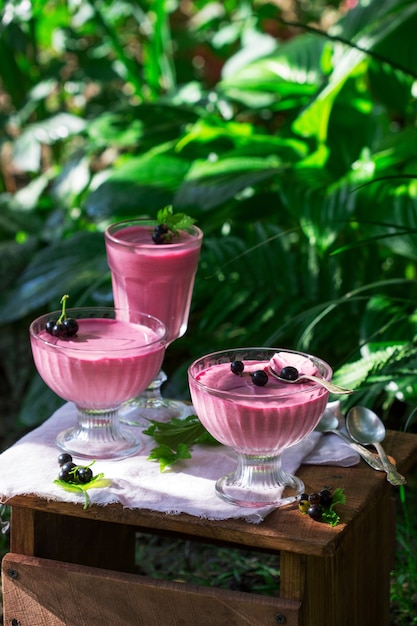 Mousse de bayas en jarrones de vidrio sobre madera en el jardín.