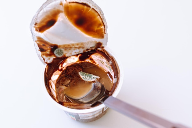 mousse de chocolate mohoso o yogur ha caducado. Producto mohoso en vaso de plástico con cuchara dentro